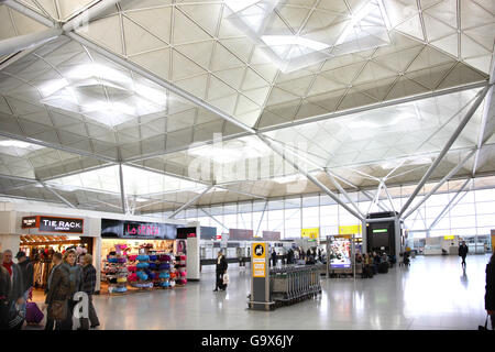 Intérieur de l'édifice principal du terminal à l'aéroport de Londres Stansted. Conçu par Norman Foster. Boutiques, salons, chariots passagers Banque D'Images