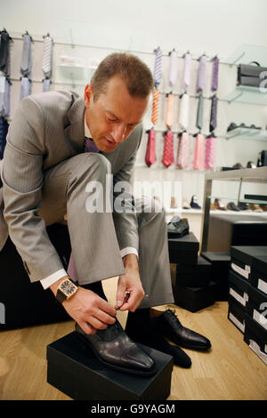 Un homme essaie de chaussures dans une pourvoirie pour hommes Banque D'Images