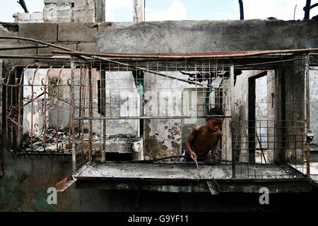 Aux Philippines. 2 juillet, 2016. Un jeune nettoie off brûlé des débris sur une fenêtre dans la ville de Quezon. Des centaines de maisons ont été englouti par un incendie dans la nuit du 1er juillet près de la route Bir à Quezon City. Selon les responsables du village, le feu a commencé lorsqu'une connexion électrique court-circuité et incendié les maisons qui sont faites de matériaux légers. Crédit : J Gerard Seguia/ZUMA/Alamy Fil Live News Banque D'Images