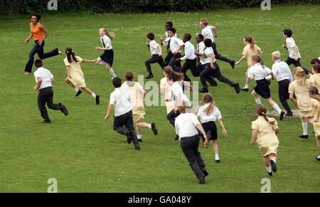 Dame Kelly Holmes est court avec des enfants autour de la propriété lors d'une visite à l'école primaire St Johns à Shirley, Croydon. Banque D'Images