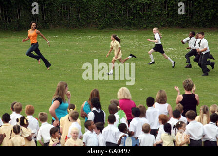 Dame Kelly Holmes est court avec des enfants autour de la propriété lors d'une visite à l'école primaire St Johns à Shirley, Croydon. Banque D'Images