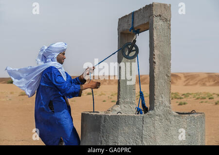 Homme marocain vêtu d'une gandora traditionnel à un puits dans le désert du Sahara. Banque D'Images