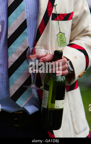 Un homme portant un Blazer de Jesus College tient une bouteille de vin et un verre pendant le dernier jour de l'Université de Cambridge mai bosses le long de la rivière Cam à Fen Ditton Cambridgeshire. Banque D'Images