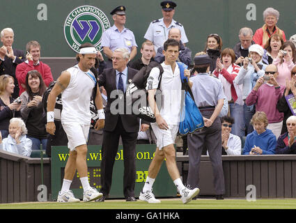 Tim Henman (au centre à droite) en Grande-Bretagne et Carlos Moya en Espagne se mettent en quatre pour prendre leur décision lors du premier match du championnat de tennis All England Lawn à Wimbledon. Banque D'Images