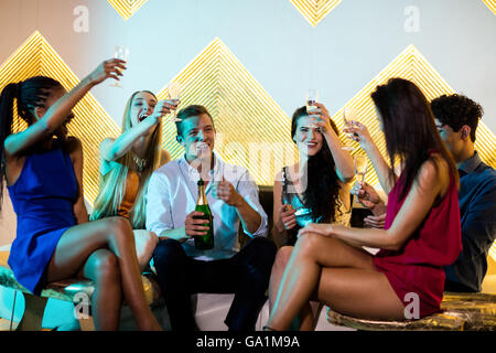 Group of smiling friends sitting on sofa et un grillage verres de champagne Banque D'Images