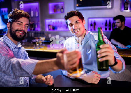 Portrait des hommes montrant verre de bière et une bouteille de bière Banque D'Images