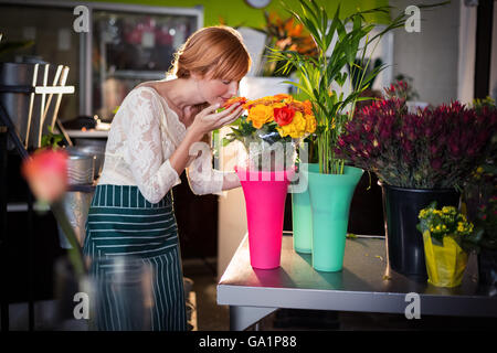 Portrait of female florist smelling rose flowers Banque D'Images