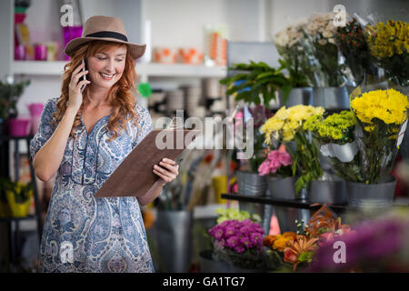 Female florist taking order on mobile phone Banque D'Images