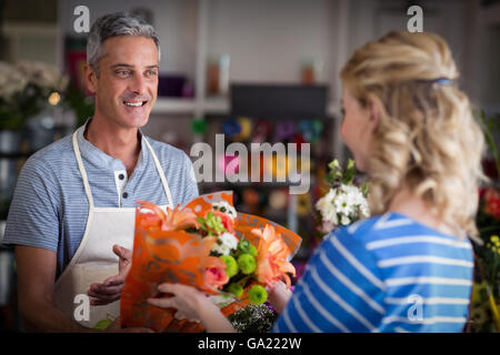 Un fleuriste bouquet de fleurs donnant au client Banque D'Images