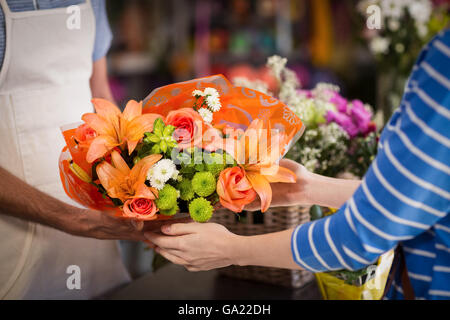 Un fleuriste bouquet de fleurs donnant au client Banque D'Images