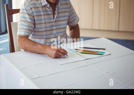 Man en utilisant un livre de coloriage Banque D'Images