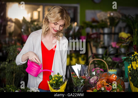 Female florist watering flowers Banque D'Images