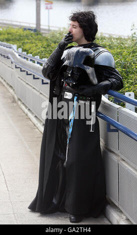 Un fan de Star Wars habillé comme Darth Vader' va à l'extérieur pour une cigarette en raison de l'interdiction de fumer à la Convention Star Wars dans l'Excel Center, Londres. Banque D'Images