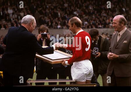 Sir Matt Busby, directeur de Manchester United, présente un tableau à Bobby Charlton au nom du club. Banque D'Images