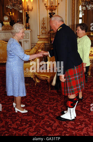 La reine Elizabeth II accueille le major Sandy Dewer des 48e Highlanders du Canada, avec Mme Dewer debout à sa droite, pendant un public privé avant sa retraite au Palais de Buckingham, à Londres. Banque D'Images