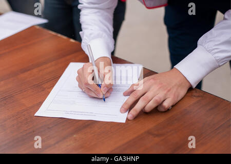 Côté masculin avec stylo en remplissant le formulaire de renseignements personnels. L'homme d'affaires au travail. Banque D'Images