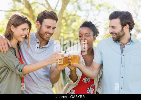 Couple toasting un verres de bière en park Banque D'Images