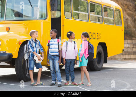 Smiling kids Standing together in front of school bus Banque D'Images