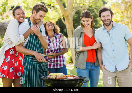 Happy friends preparing a barbecue in park Banque D'Images