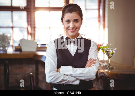 Smiling female bartender standing with arms crossed Banque D'Images