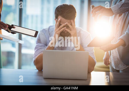 Frustrés businessman sitting on desk with hand on head Banque D'Images
