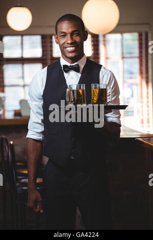 Bartender holding plateau de service avec des verres de bière Banque D'Images