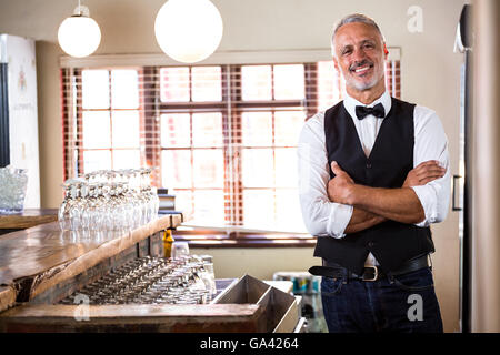 Portrait of smiling bartender standing with arms crossed Banque D'Images