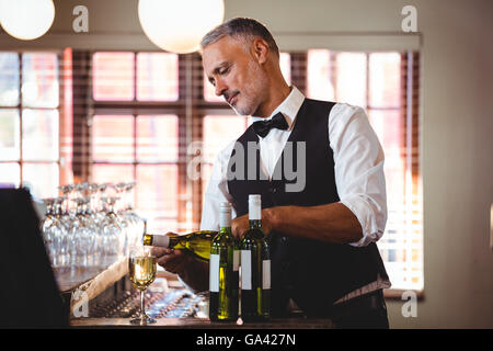 Bartender pouring red wine in a glass Banque D'Images