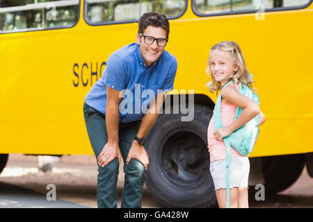 Lycéenne et Smiling teacher standing in front of school bus Banque D'Images