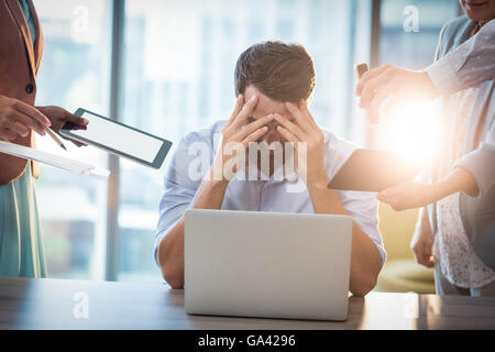 Frustrés businessman sitting on desk with hand on head Banque D'Images