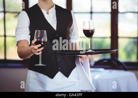 Section intermédiaire de serveuse offrant un verre de vin rouge Banque D'Images