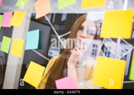 Thoughtful woman sur sticky notes Banque D'Images