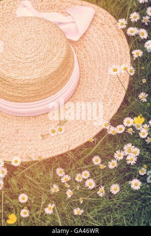 Chapeau de paille sur une pelouse daisy avec un filtre solaire vintage Banque D'Images