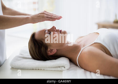 Les mains du thérapeute recadrée performing reiki à femme Banque D'Images