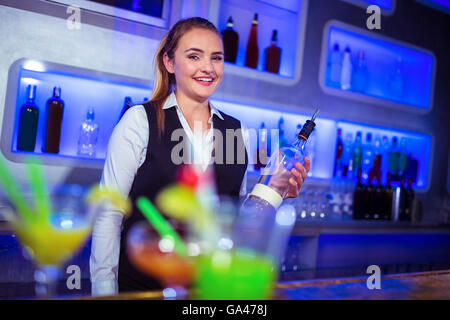 Portrait of smiling bartender holding bottle Banque D'Images