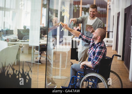 Businessman aider handicap collègue in creative office Banque D'Images