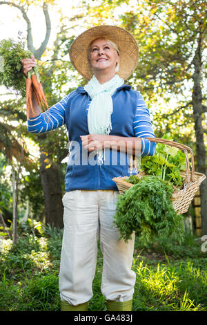 Jardinier heureux debout avec des légumes frais au jardin Banque D'Images