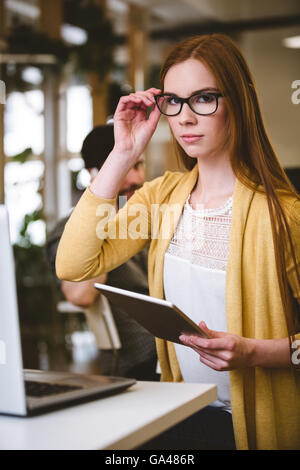 Confident businesswoman adjusting eyeglasses Banque D'Images