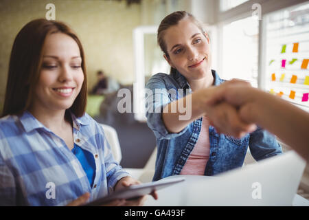 Happy businesswomen shaking hands in office Banque D'Images