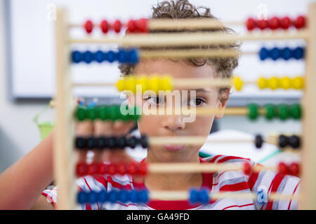 Garçon jouant avec abacus in classroom Banque D'Images