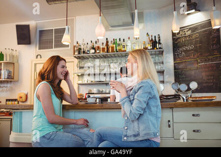 Happy friends talking at counter in coffee shop Banque D'Images