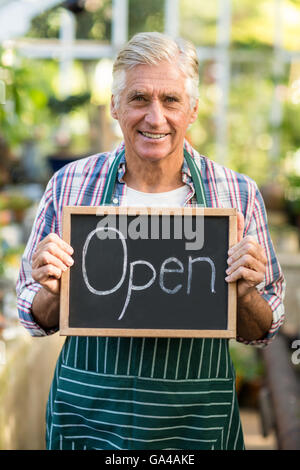 Mature owner holding open sign placard Banque D'Images