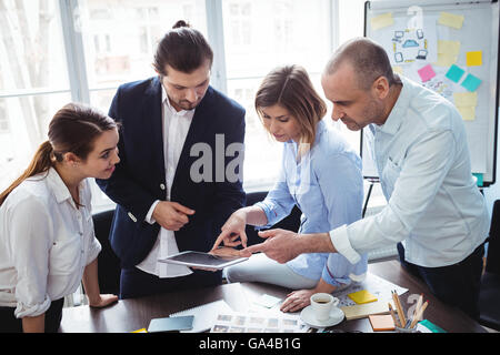 Editors using digital tablet in meeting room Banque D'Images