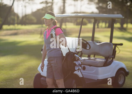 Femme debout par voiturette de golf Banque D'Images