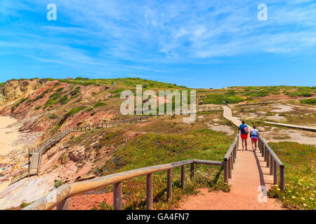 Couple de touristes marcher sur la passerelle de la plage Praia do Amado, endroit célèbre pour le surf, la région de l'Algarve, Portugal Banque D'Images