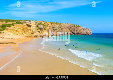 Les surfeurs sur l'eau de mer sur la plage de sable de Zavial, Portugal Banque D'Images