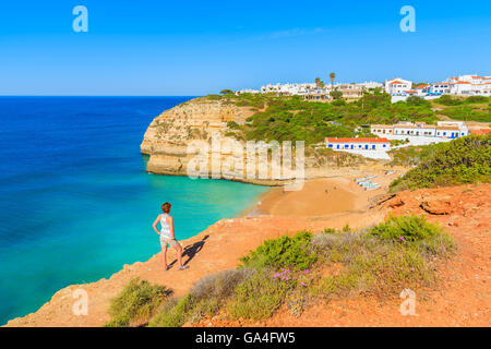 Jeune femme debout touristiques sur falaise et à la plage de Benagil, Algarve, Portugal Banque D'Images