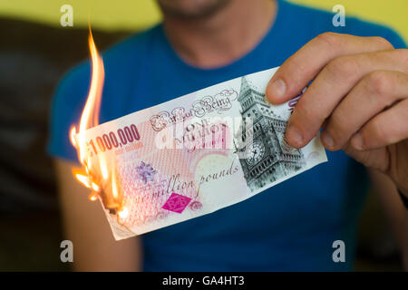 Un homme en train de mettre le feu à un million pound note, symbole de l'effondrement de l'économie britannique post brexit ; de l'argent en fumée Banque D'Images