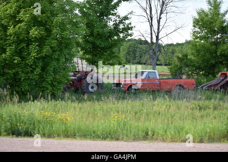 L'équipement agricole et une vieille Chevy truck dans un champ avec une vache à l'arrière-plan Banque D'Images