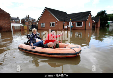 Des tempêtes ont frappé le Royaume-Uni.Une femme est emmenée de sa maison à un sol sec dans une zone inondée près de la rivière Severn à Gloucester. Banque D'Images